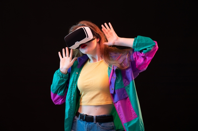 a front view modern young lady in colorful coat orange t shirt playing and trying vr on the black background gaming interactive play